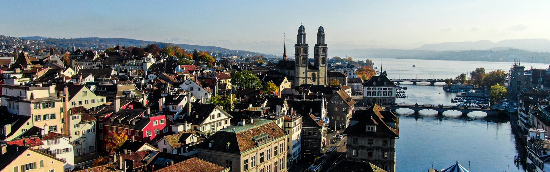 Zurich Grossmünster twin towers with Lake Zurich and bridge at golden hour